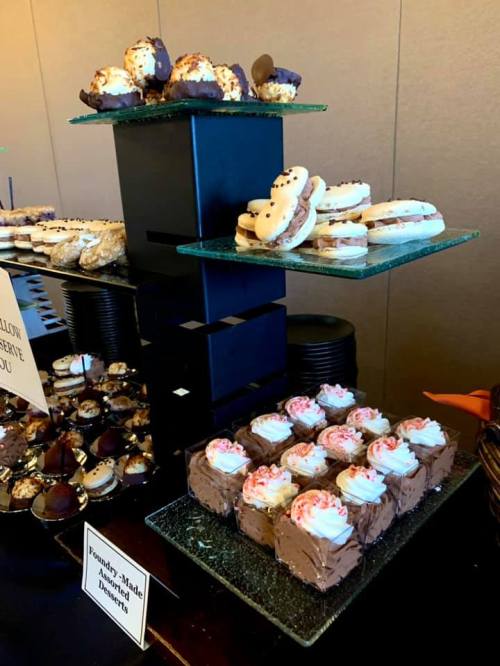 A display of assorted desserts, including cookies, brownies, and pastries, arranged on glass stands.