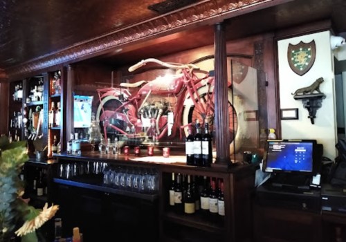 A wooden bar with shelves of liquor, a vintage red bicycle displayed, and a TV in a cozy setting.