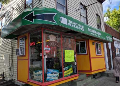 A colorful restaurant exterior with a green awning, signs for Mexican food, and an "Open" sign in the window.