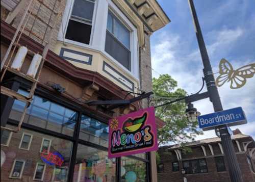 Sign for Neno's Gourmet Mexican Street Food outside a building on Boardman Street, with a blue sky in the background.