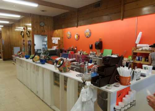 A colorful café interior with a service counter, decorative items, and various food containers on display.