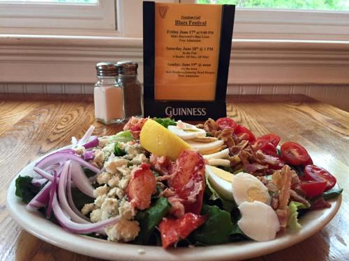 A colorful salad with lettuce, tomatoes, onions, and toppings, next to a menu for a festival at a restaurant.