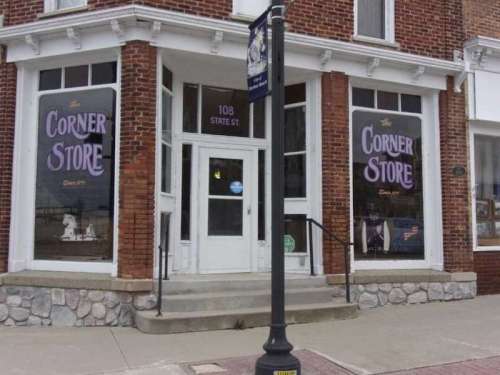 A brick building with large windows displaying "Corner Store" signage and a street lamp in front.