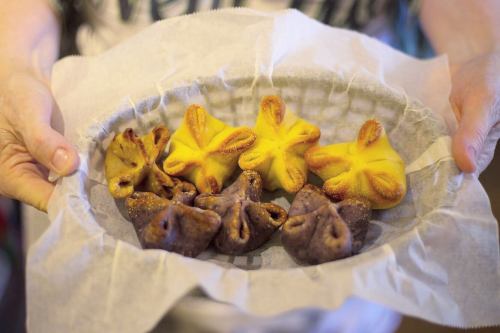 A person holds a plate of colorful pastries, featuring yellow and purple star-shaped treats on parchment paper.
