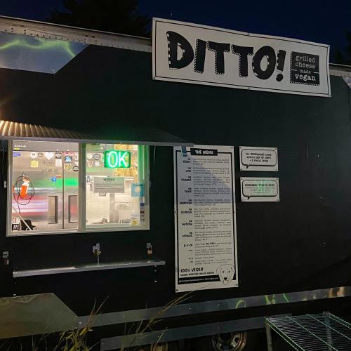 A food truck named "DITTO!" with a menu board and brightly lit windows at night.