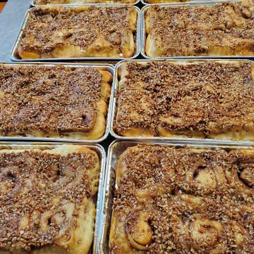 Trays of freshly baked cinnamon rolls topped with a crunchy pecan streusel.
