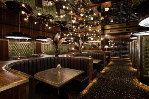 Elegant restaurant interior with mirrored walls, plush seating, and ambient lighting, creating a luxurious atmosphere.