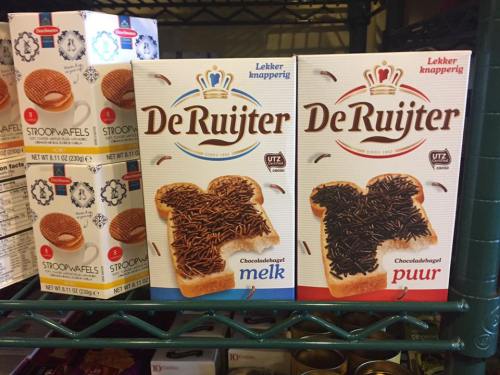 Two boxes of De Ruijter chocolate sprinkles on a shelf, one milk chocolate and one dark chocolate, alongside stroopwafels.