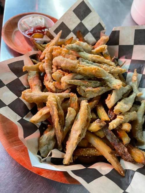A basket of crispy fried fish strips and French fries, served with a side of ketchup.