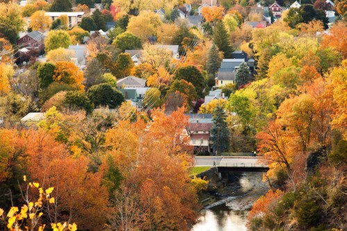 A vibrant autumn landscape featuring colorful trees and houses along a winding river.