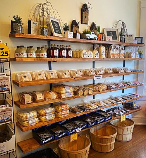 A wooden shelf displays various baked goods and jars, with baskets below and decorative items on top.