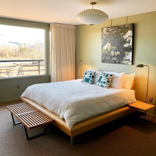 A cozy bedroom with a large bed, decorative pillows, and a view of nature through a window.