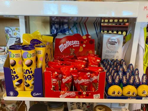 A shelf displaying various chocolate products, including Maltesers, Cadbury mini eggs, and colorful Easter-themed treats.