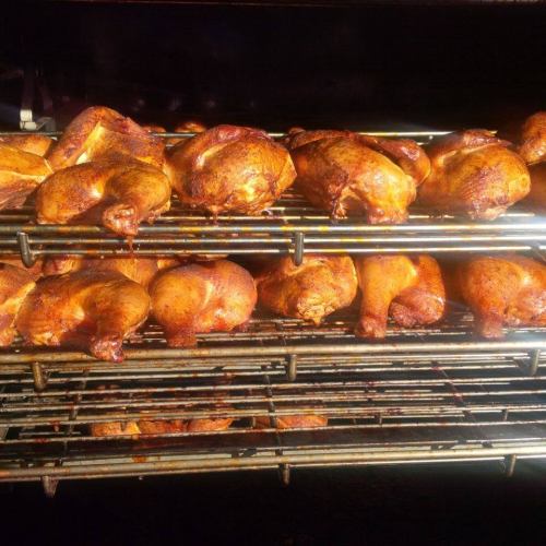 A close-up of golden-brown roasted chicken pieces on a grill, evenly cooked and arranged on metal racks.