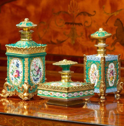 Three ornate decorative vases with floral designs and gold accents, displayed on a polished wooden surface.
