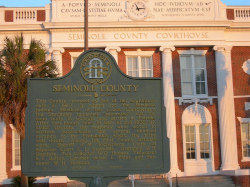 Historic Seminole County Courthouse with a green historical marker in front, set against a clear sky.