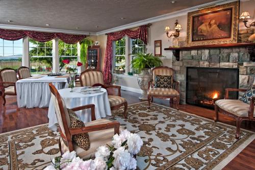 Cozy living room with a stone fireplace, elegant furniture, and large windows showcasing greenery outside.