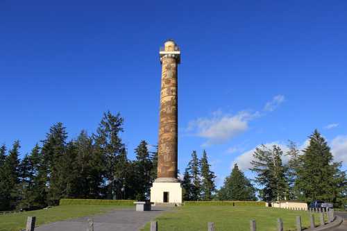 A tall, cylindrical monument stands surrounded by trees under a clear blue sky.