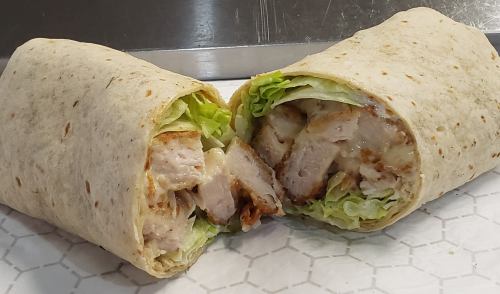 A cut tortilla wrap filled with grilled chicken and lettuce, showcasing its contents.
