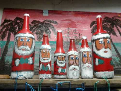 A row of painted bottles resembling Santa Claus, with festive colors and expressions, set against a tropical background.