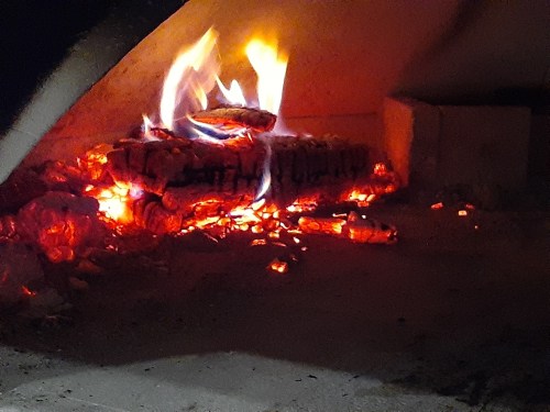 A close-up of glowing embers and flames rising from a log in a fireplace, creating a warm, cozy atmosphere.