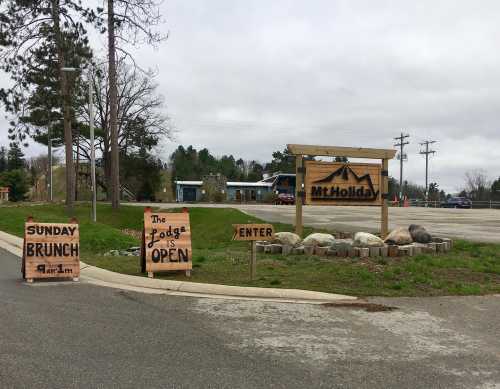 Signage for Mt. Holiday featuring "Sunday Brunch" and "The Lodge is Open" with a rustic wooden design.