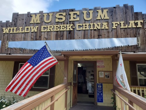 Sign for the Willow Creek-China Flat Museum, featuring an American flag and a California state flag at the entrance.