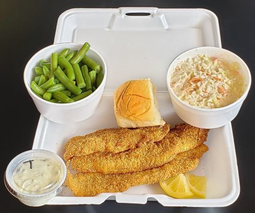 A takeout meal featuring fried fish fillets, green beans, coleslaw, a roll, and a side of tartar sauce with a lemon wedge.