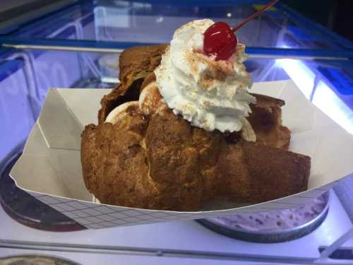 A delicious dessert featuring a pastry topped with whipped cream, a cherry, and a sprinkle of cinnamon.