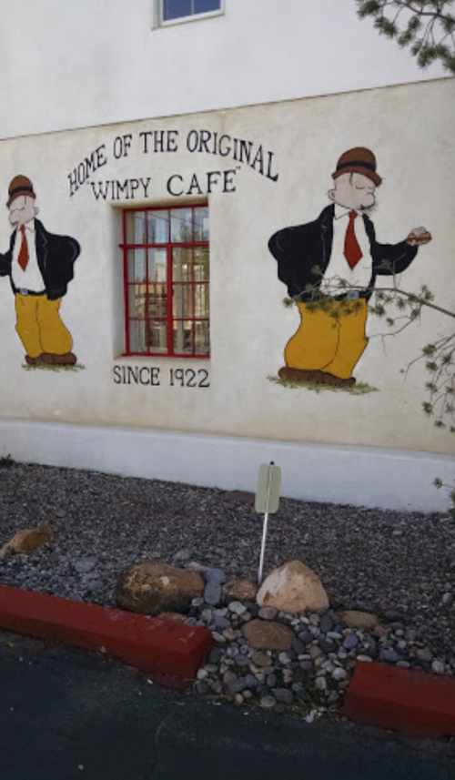 Mural of two cartoon characters in suits on a wall, advertising the "Home of the Original Wimpy Café" since 1922.