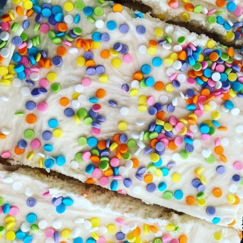 Close-up of a frosted cake topped with colorful sprinkles in various shapes and sizes.