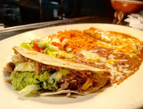 A plate featuring a taco with lettuce and guacamole, alongside rice, beans, and an enchilada.