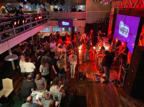 A lively music venue with a band performing on stage and a crowd dancing and enjoying the atmosphere.