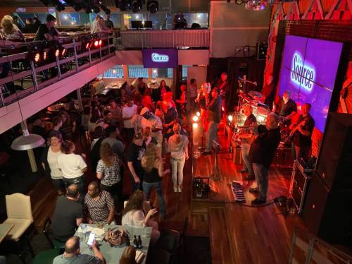 A lively music venue with a band performing on stage and a crowd dancing and enjoying the atmosphere.