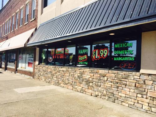 Exterior view of a restaurant with colorful signs advertising happy hour and $1.99 margaritas.