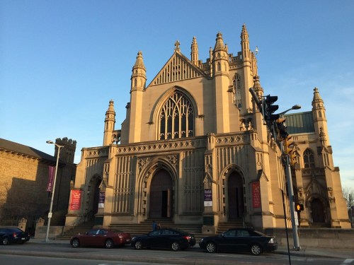A large, ornate stone church with tall spires and intricate architectural details, set against a clear blue sky.