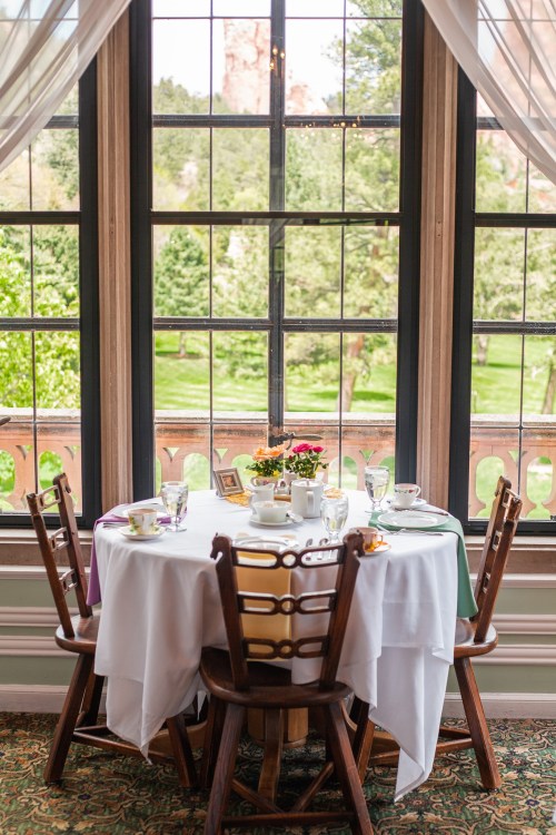 A beautifully set dining table with flowers, overlooking a scenic view through large windows.