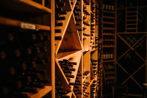A dimly lit wine cellar with wooden racks filled with numerous wine bottles.