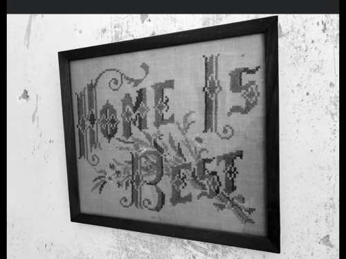 Framed cross-stitch artwork with the text "Home is Best" on a textured background.