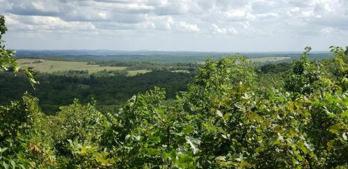 A panoramic view of lush green hills and valleys under a cloudy sky.