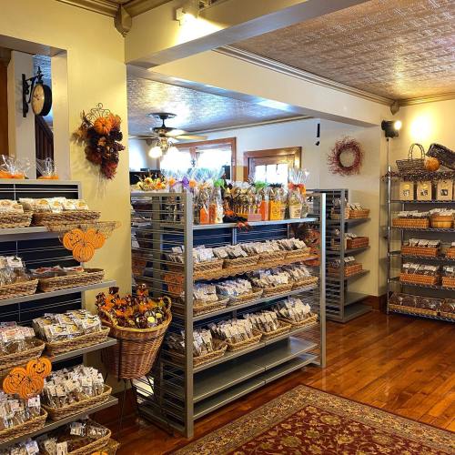 A cozy shop interior filled with shelves of packaged treats and autumn decorations, featuring warm wood tones and a welcoming atmosphere.