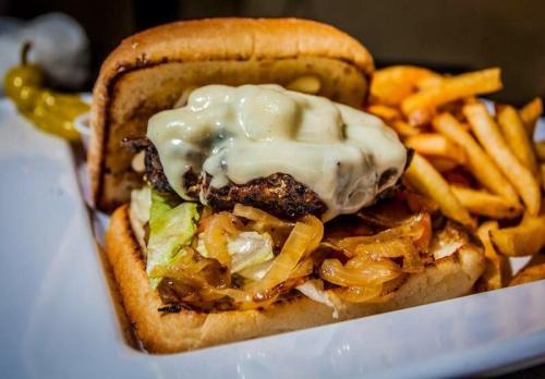A juicy burger with melted cheese, lettuce, and sautéed onions, served with crispy French fries on the side.