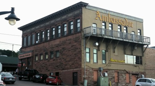 A large, historic building with the word "Ambassador" prominently displayed, featuring multiple windows and a balcony.