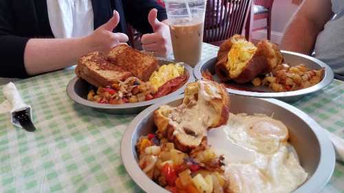 Three plates of breakfast featuring French toast, eggs, bacon, and mixed potatoes, with iced coffee in the background.