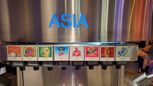 A beverage dispenser labeled "ASIA" with various soda options, including Fanta and Royal, in colorful logos.