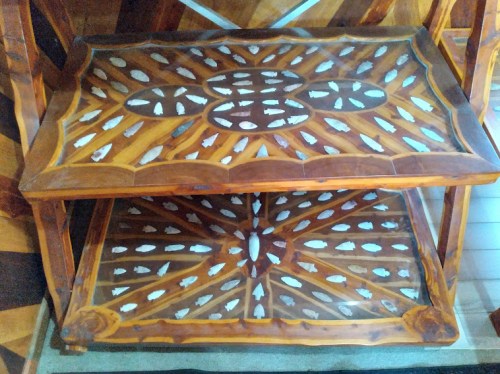 A wooden table with intricate inlay designs featuring geometric patterns and a two-tiered structure.