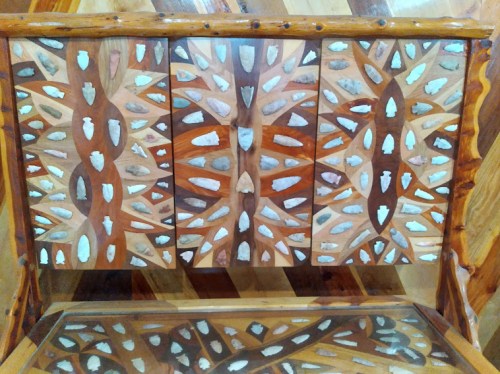 Intricate wooden cabinet with decorative inlays resembling arrowheads, showcasing a unique geometric pattern.