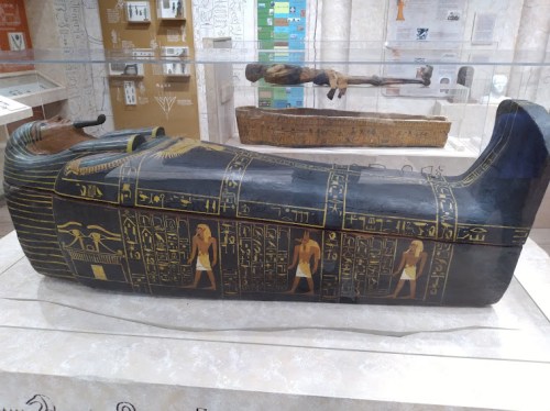 A decorated ancient Egyptian sarcophagus with hieroglyphics and figures, displayed in a museum.