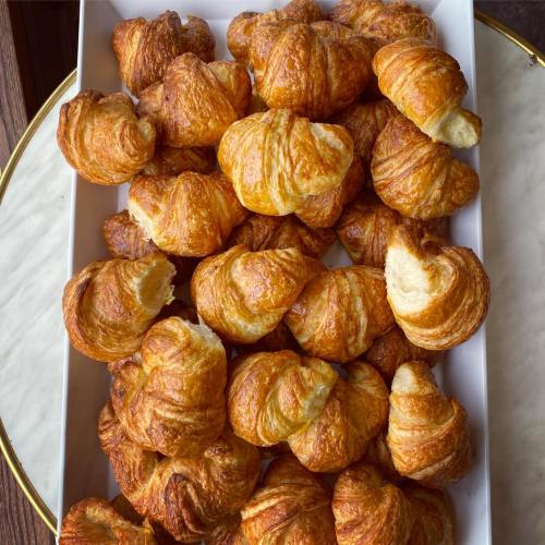A platter filled with golden, flaky croissants arranged neatly.