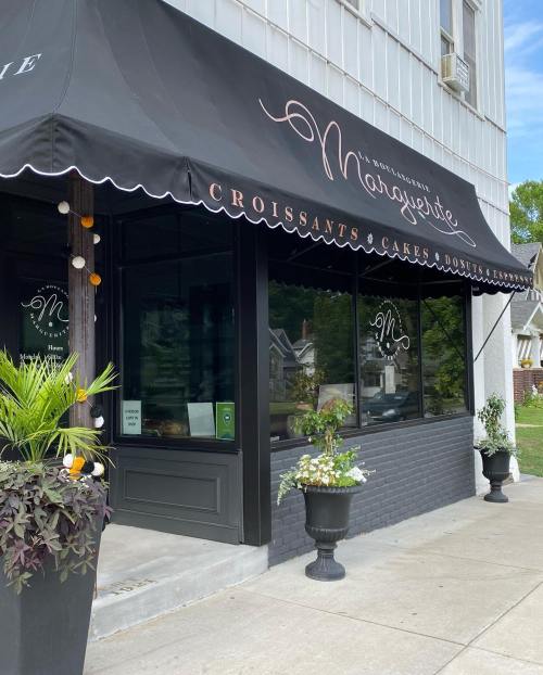 A bakery storefront with a black awning, featuring the name "Nanyette" and decorative plants on either side.